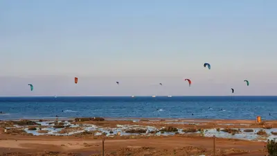 a group of people flying kites over the ocean at El Gouna Mangroovy Residence Sea View - kitesurfing in Hurghada