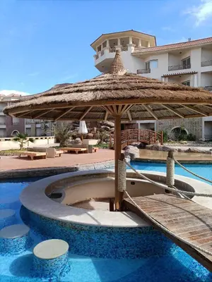 a swimming pool with a umbrella and a resort at Royal Beach Hurghada in Hurghada