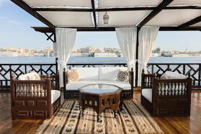 a porch with a couch and chairs and a table at Farouz El Nil I Nile Cruise - Every Monday from Luxor for 07 & 05 Nights in Ţawd