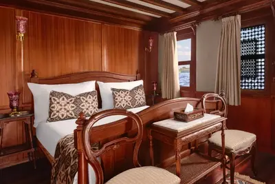 a bedroom with a bed and a table and a chair at Farouz El Nil II Nile Cruise - Every Monday from Luxor for 07 & 05 Nights in Luxor