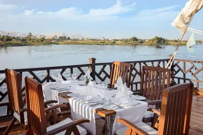 a table set up on a deck with a view of a river at JAZ Farouz El Nil III Nile Cruise - Every Saturday from Luxor for 07 & 05 Nights in Luxor