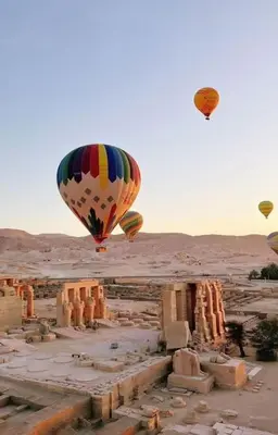 two hot air balloons flying over an ancient city at Tibs mountain view in Al Aqālitah