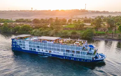 a large blue cruise ship on the water at 4-Day 3-Night Guided Nile Cruise from Aswan to Luxor every Monday, Wednesday & Friday Departures in Aswan