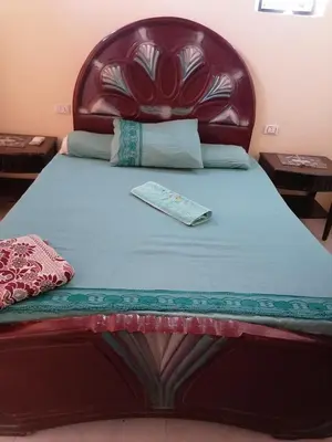 a bed with a leather headboard and a book on it at Djorf apartments in Al Aqālitah