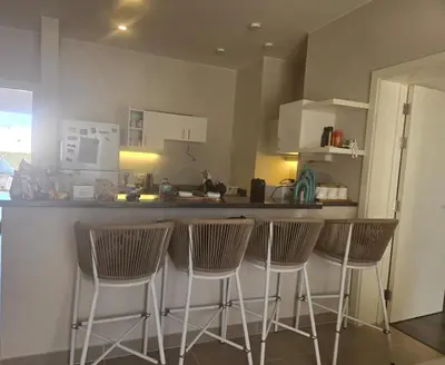 a kitchen with a bar with four bar stools at El Gouna, Cyan 2-Bedroom Ground Floor in El Gouna