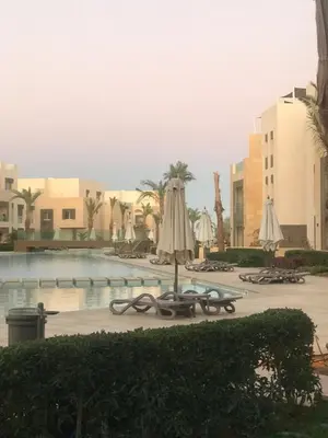 a swimming pool with umbrellas and chairs and a hotel at Mangroovy M7-4A-03 in Hurghada