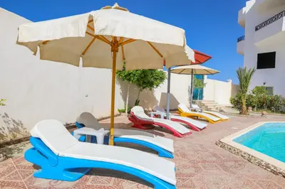 a group of chairs and an umbrella next to a swimming pool at la bonita studio in Hurghada