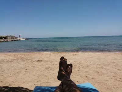 a person laying on the beach with their feet up at Chalet front the beach in Hurghada