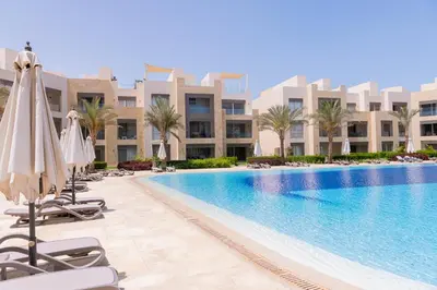 a pool at a resort with umbrellas and chairs at Modern apartment with large pool & beach access in Hurghada
