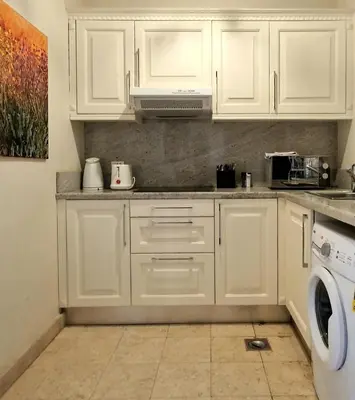 a white kitchen with white cabinets and a washer at Nubian Style Apartment, South Marina, El Gouna in Hurghada