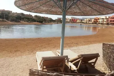 two chairs and an umbrella on a beach at Style Apartment in nubian design at lagoon in Hurghada
