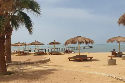 a beach with chairs and umbrellas and the ocean at Hurghada Cosy Apart in Hurghada