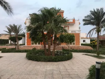 a building with palm trees in front of it at Hurghada-Magawish Villa 4 in Hurghada