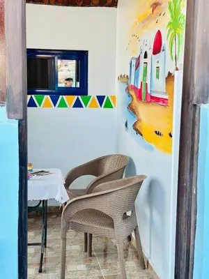 a room with two chairs and a table and a painting at Bakar Nubian Guest House in Aswan