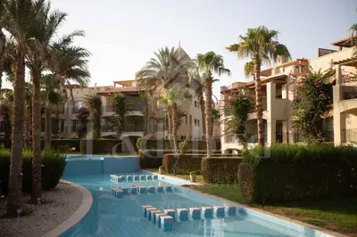 a resort swimming pool with palm trees and buildings at Ladybird - Veranda Beach House in Hurghada