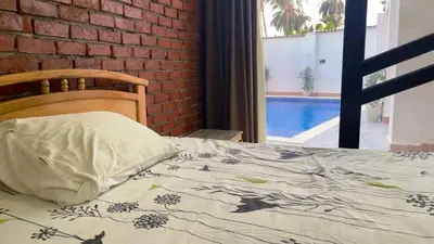 a bed with a pillow on it with a brick wall at El Hady Apartments with Swimming Pool in Luxor