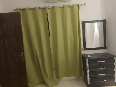 a bathroom with green curtains and a mirror and a dresser at one bed Apartment In Al Makramia in Hurghada