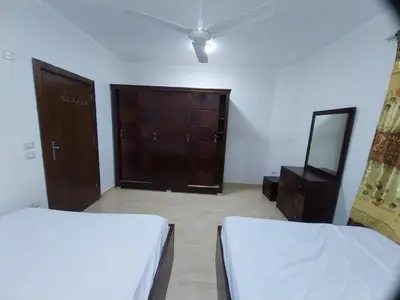 a bedroom with two beds and a dresser and a mirror at Emad villa in Hurghada