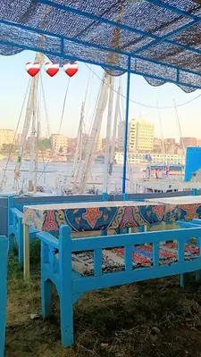 two blue benches sitting under a blue umbrella at Onaty Narty Guest house Nile view in Aswan