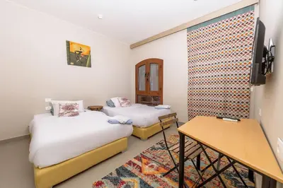 a room with two beds and a table and a desk at Sabina Lagoon view 2BR Apartment in Hurghada