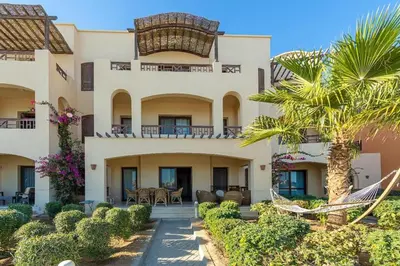 a large building with palm trees in front of it at Sabina Lagoon view 2BR Apartment in Hurghada