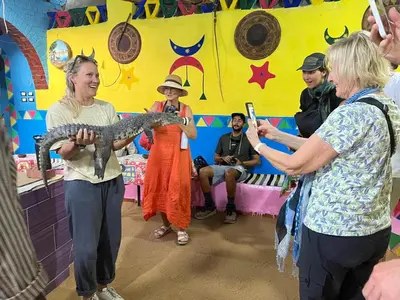 a woman holding a python in a room with people at Alara Hostel 