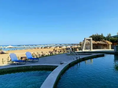 a swimming pool with two blue chairs and a beach at Turtles Beach resort hourghada Studio view sea view pool private beach Pools balcony security Cafe and restaurant on pool jacuzzi air-condition sunny a large balcony in Hurghada