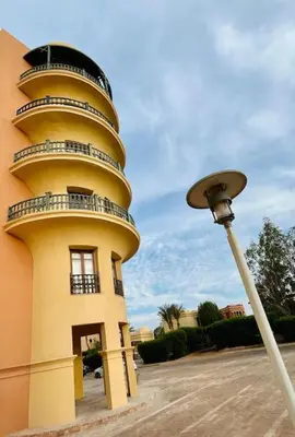 a yellow building with a round tower next to a street light at SunShine AbuTig Marina in Hurghada