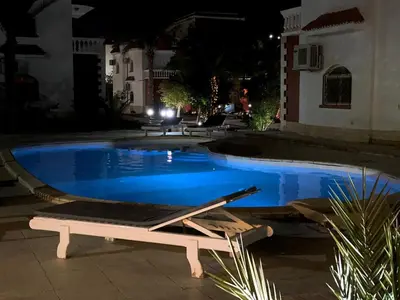 a swimming pool at night with a lounger in front at فيلا 1☆ in Hurghada