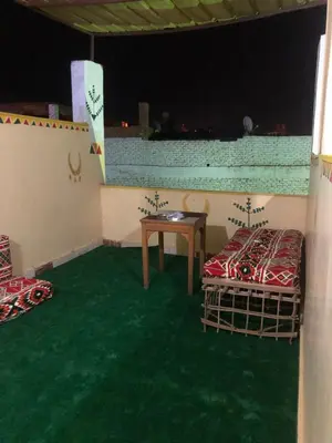 a room with two beds and a table and green carpet at NUB Guest House in Aswan