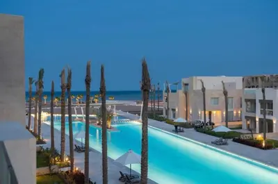 a large swimming pool with palm trees and the ocean at Fabulous Sea view 1 BR & private Garden to the pool at Mangroovy in Hurghada