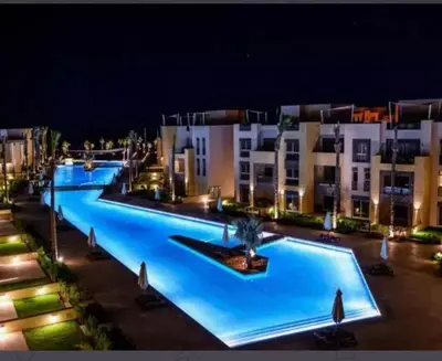 an empty swimming pool at night with buildings at Fabulous Sea view 1 BR & private Garden to the pool at Mangroovy in Hurghada