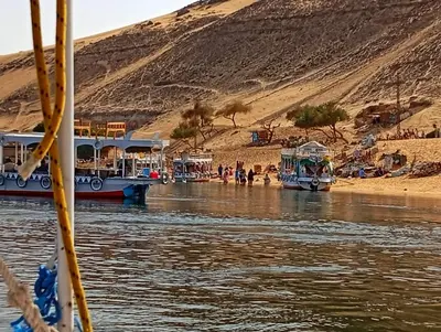 two boats docked on the shore of a river at Kashta Nubian Guest Houst in Aswan