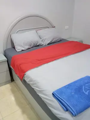 a white bed with red and blue sheets and pillows at Abeer Guest House in Luxor