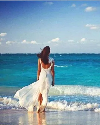 a woman in a white dress walking on the beach at Cecelia Resort Hurghada in Hurghada