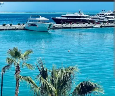 two boats are docked in a harbor with palm trees at Sheraton Plaza Marina Blast 2 bedroom 2 bathroom in Hurghada