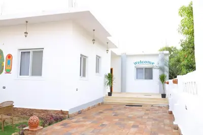 a white house with a welcoming sign on it at Diamond Guest House in Luxor