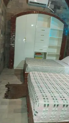 a bedroom with two beds and a brick wall at Shahhat Flat in Luxor