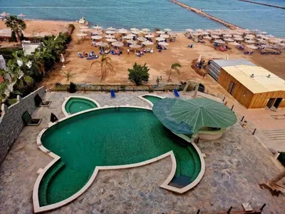 a resort with a swimming pool and a beach with umbrellas at Hurghada Concierge at Turtles Beach Resort in Hurghada