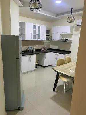 a kitchen with white cabinets and a table and a refrigerator at Casablanca beach family suites in Hurghada