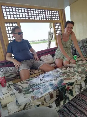 a man and a woman sitting on a bed at Aswan Felucca sailing boat and Hotel in Aswan