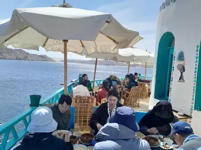 a group of people sitting at a table on a boat at Miskaa Nubian House in Naj‘ Tinjār