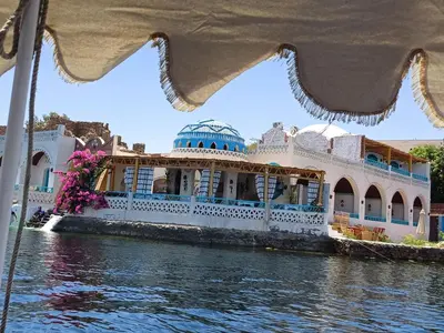 a boat in the water with a building at Miskaa Nubian House in Naj‘ Tinjār