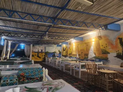 a restaurant with tables and chairs and a mural on the wall at Endo Mando in Shellal