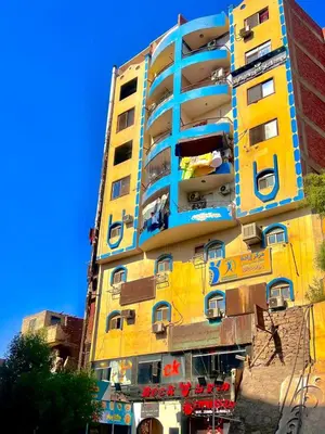 a yellow and blue building with people on the balconies at شقة مميزة بجوار كورنيش النيل اسوان - عائلات فقط in Aswan