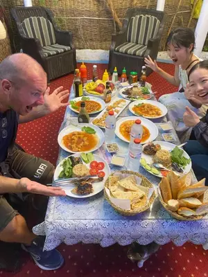 a group of people sitting around a table with food at peace garden hostel & camp in Luxor