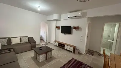 a living room with a couch and a tv on the wall at Bay View Sahl hasheesh Apartment Hurghada in Hurghada