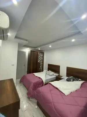 two beds in a room with purple sheets at Fanadir bay in Hurghada