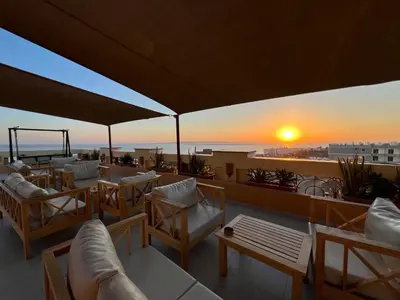a rooftop patio with chairs and tables and a sunset at Lazur Sea & City Apartment's - El Hadaba, Hurghada - Egypt in Hurghada
