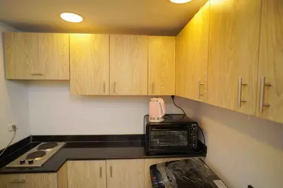 a microwave in a kitchen with wooden cabinets at كمباوند فلورنزا خمسين in Hurghada